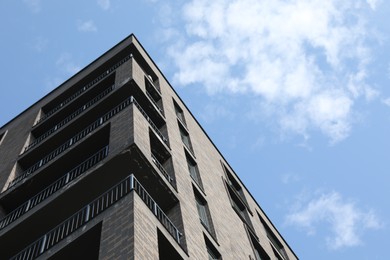 Photo of Modern building with big windows against blue sky outdoors, low angle view. Space for text