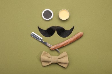 Photo of Artificial moustache and barber tools on khaki background, flat lay