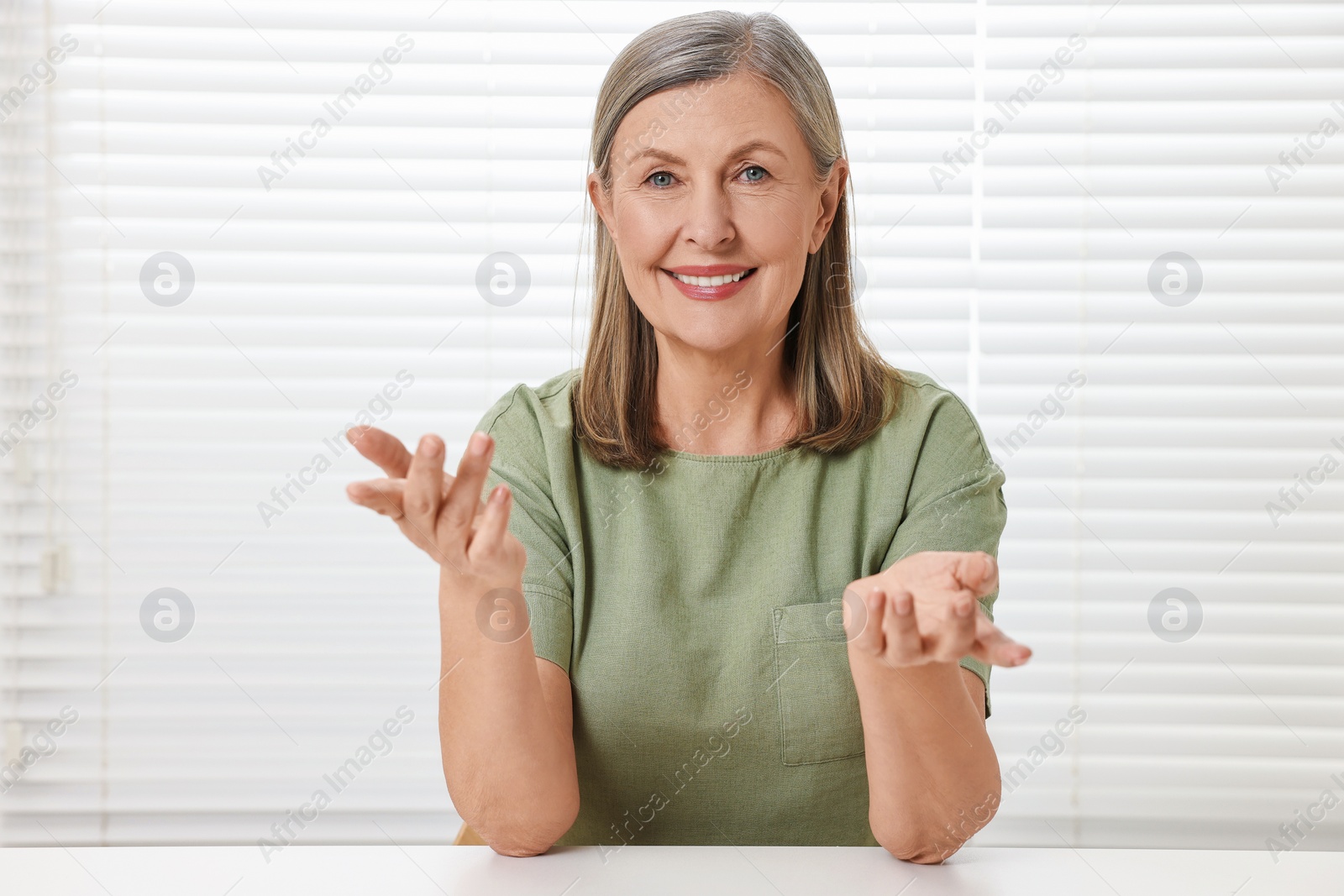 Photo of Happy woman at white table in room