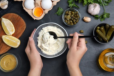 Photo of Woman with tartar sauce at black table, top view