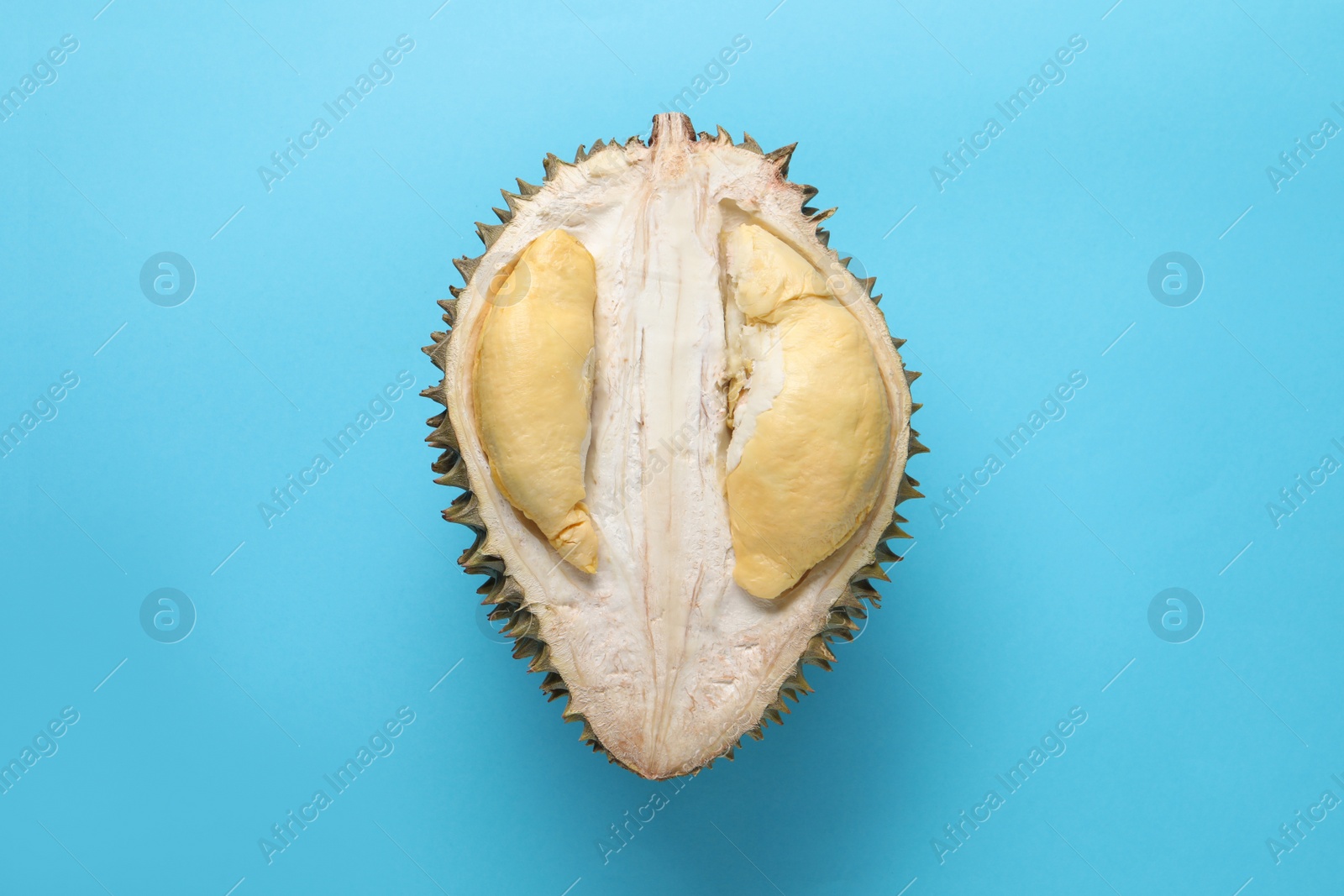 Photo of Half of fresh ripe durian on light blue background, top view