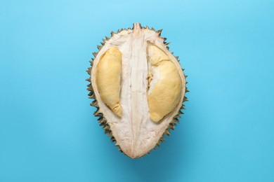 Photo of Halffresh ripe durian on light blue background, top view