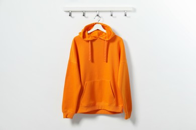 Photo of Hanger with orange hoodie on white wall