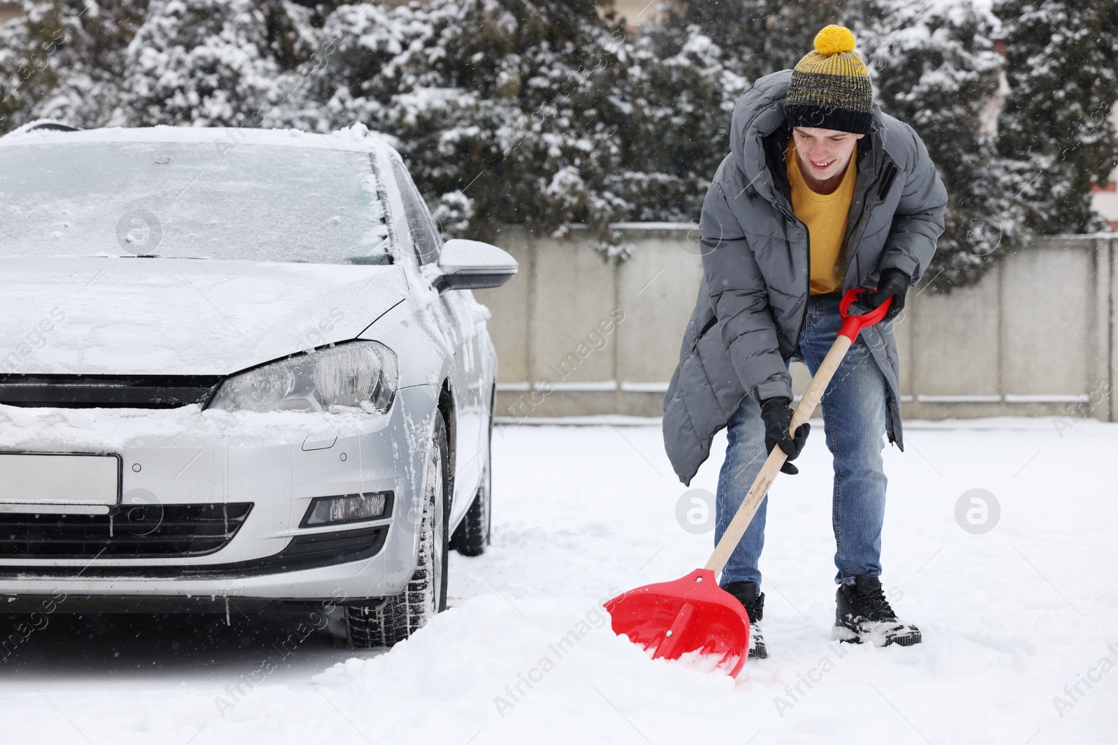 Photo of Man removing snow with shovel near car outdoors