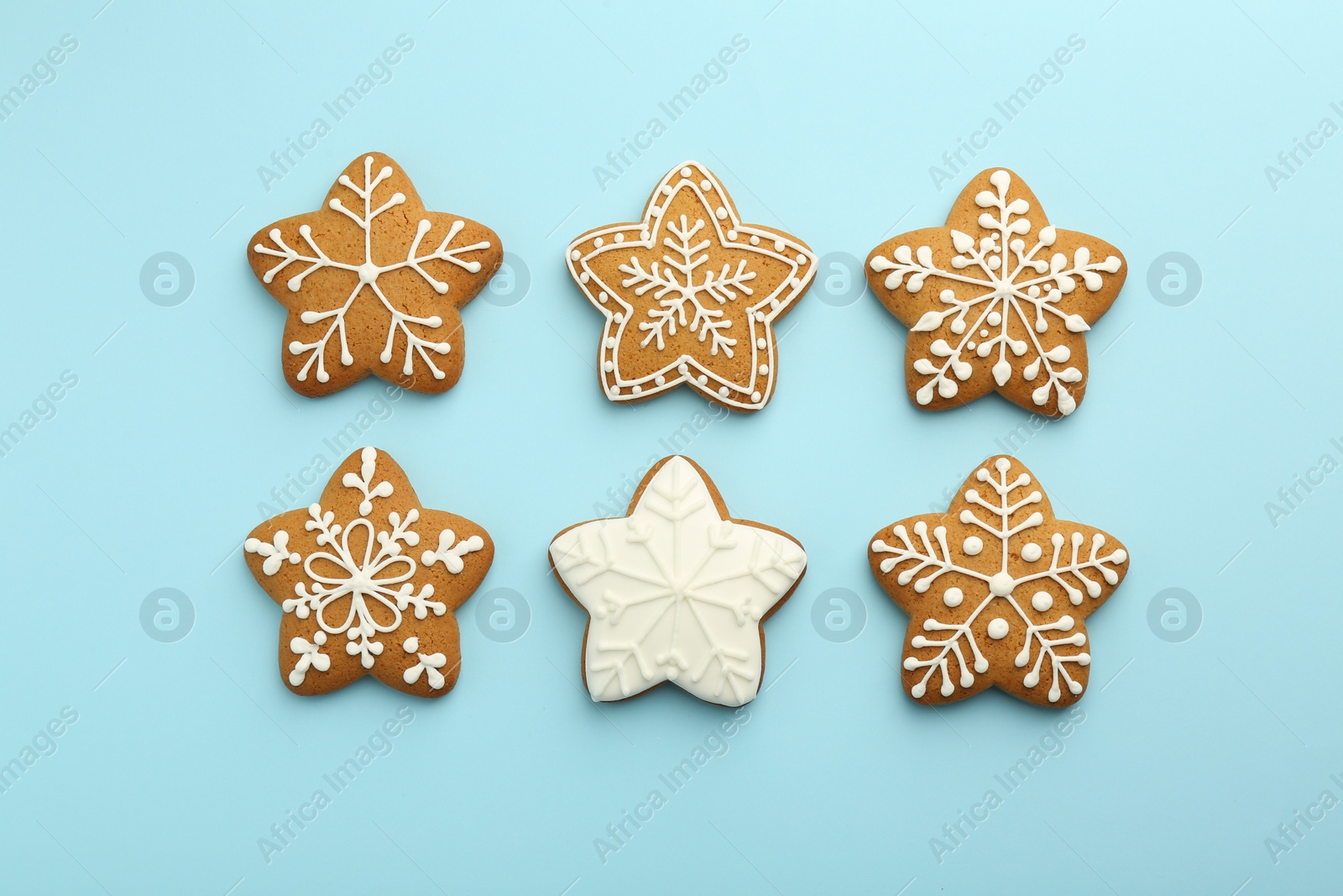 Photo of Tasty star shaped Christmas cookies with icing on light blue background, flat lay