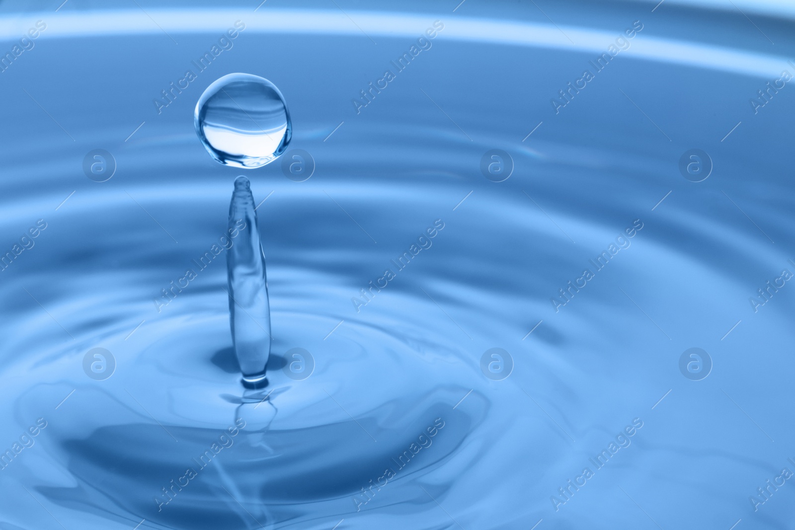 Photo of Splash of clear water with drop on light grey background, closeup. Space for text