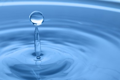 Splash of clear water with drop on light grey background, closeup. Space for text