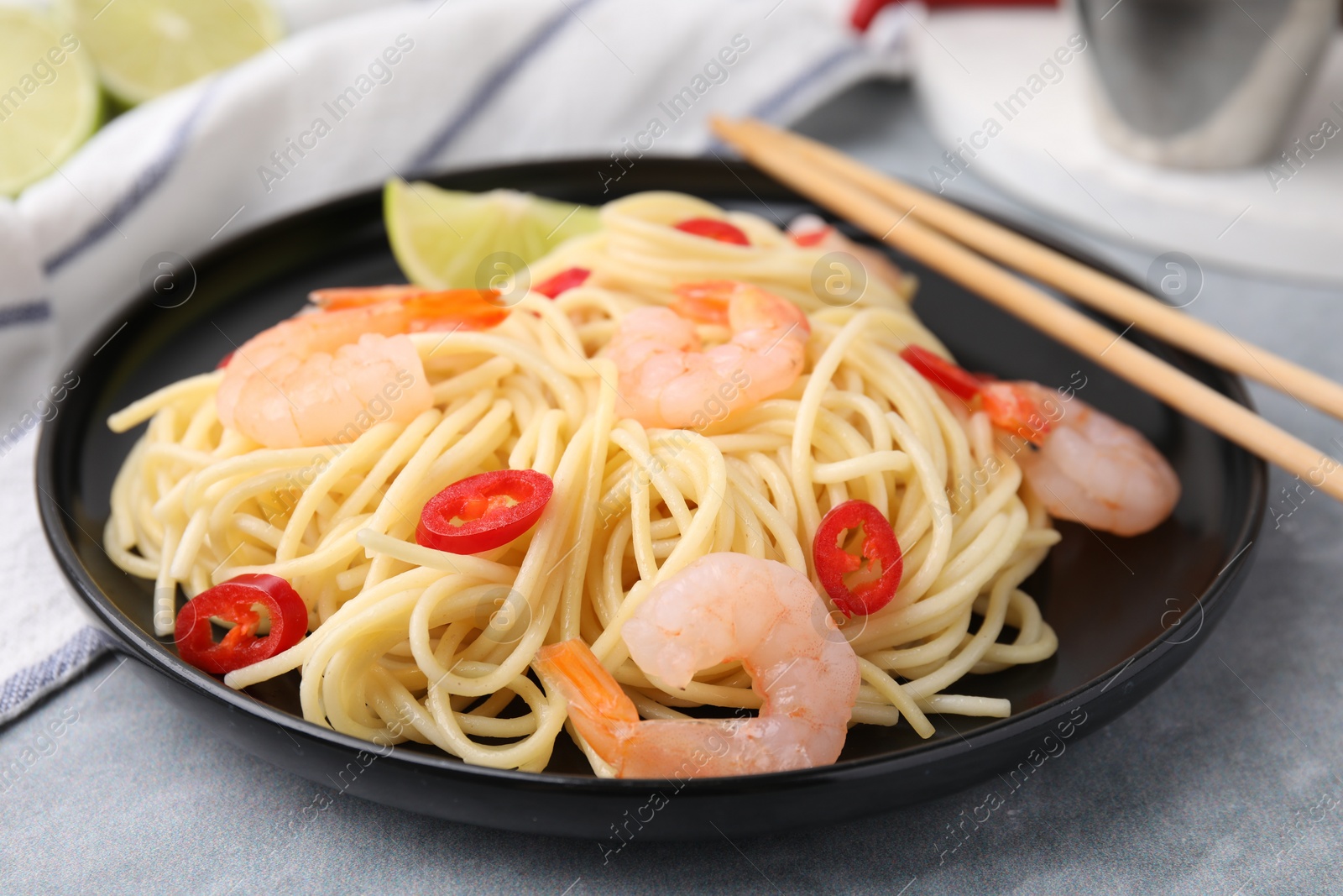 Photo of Tasty spaghetti with shrimps and chili pepper on grey table, closeup