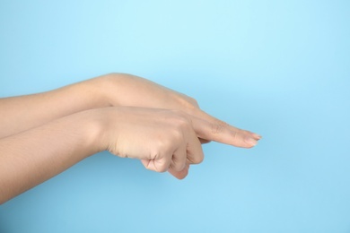 Woman showing word same on color background, closeup. Sign language