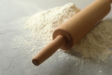 Photo of Flour and rolling pin on grey table, closeup