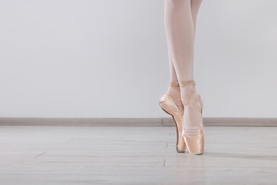Photo of Young ballerina in pointe shoes practicing dance moves at studio, closeup. Space for text