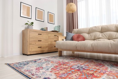 Photo of Beautiful rug, sofa and chest of drawers indoors