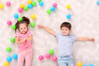 Cute little children with toys on floor indoors, top view