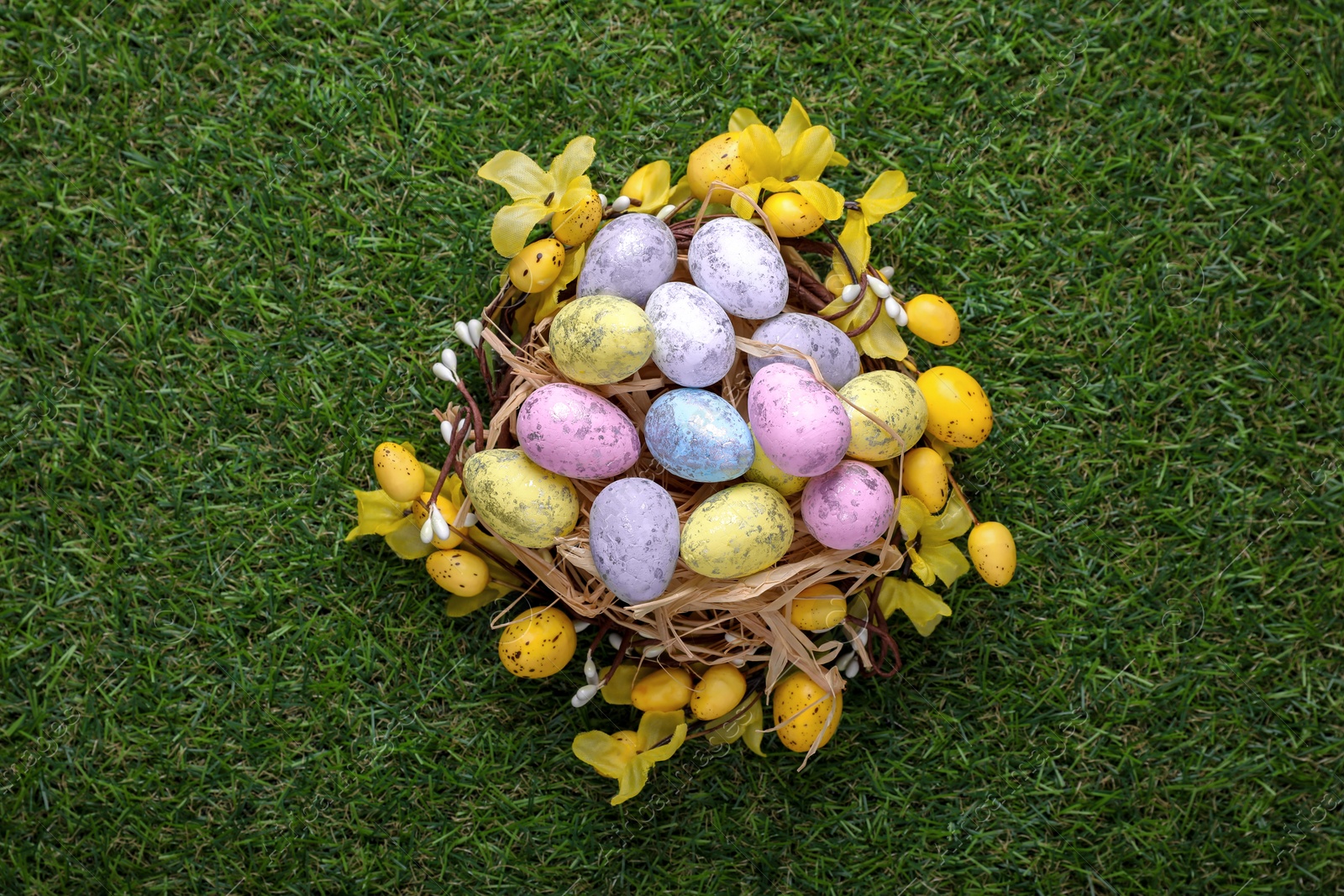 Photo of Festively decorated Easter eggs on green grass, top view
