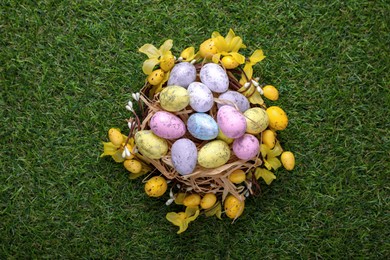 Festively decorated Easter eggs on green grass, top view