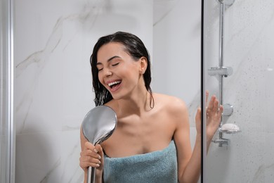 Photo of Beautiful young woman with towel singing while taking shower