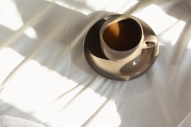 Photo of Cup of aromatic coffee on bed in morning, above view. Space for text