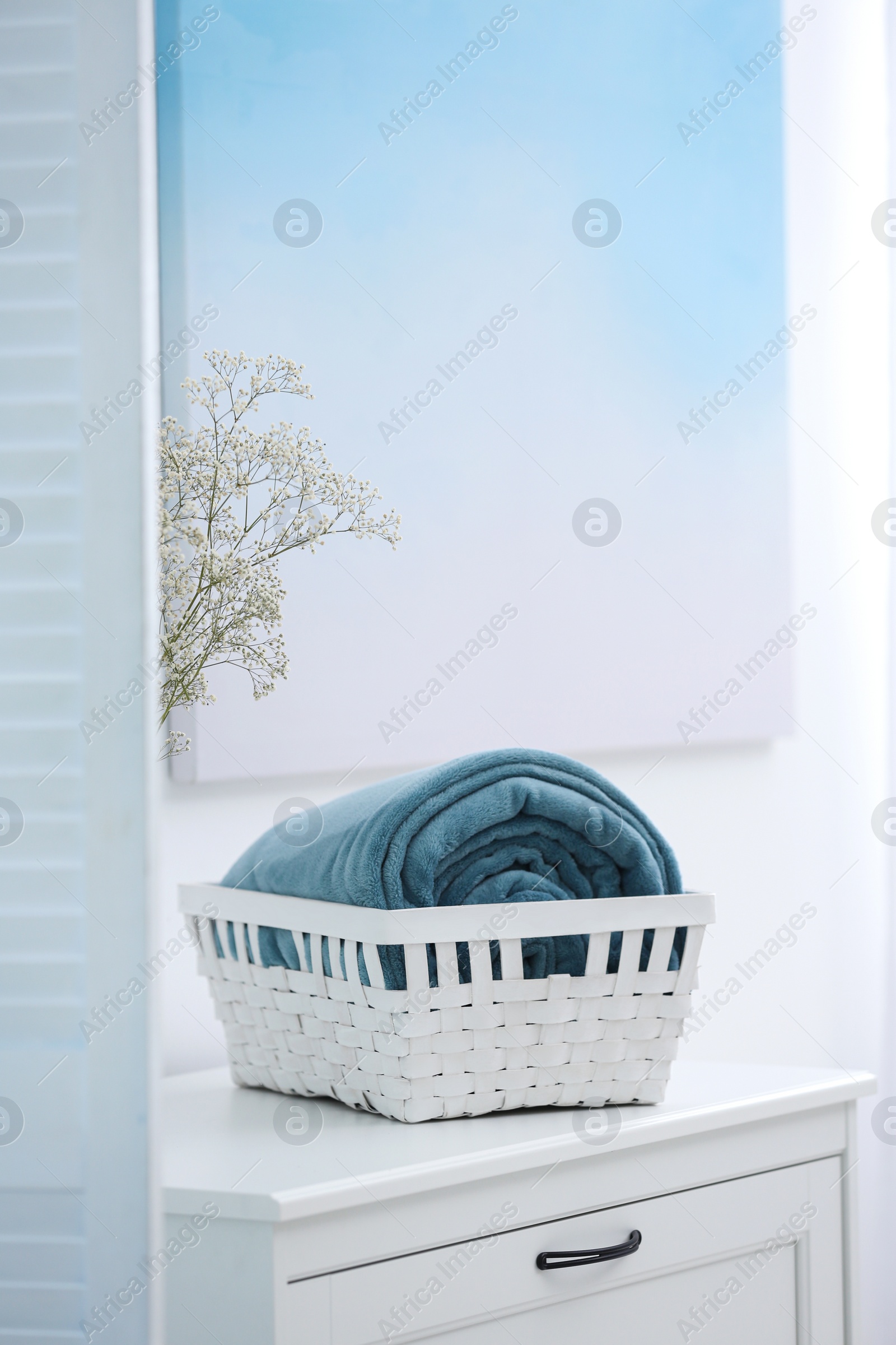 Photo of Basket with soft plaid on commode in room