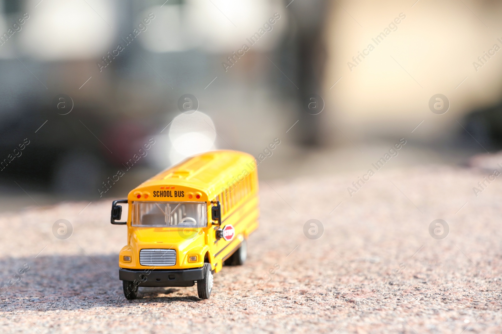 Photo of Yellow toy school bus on road outdoors. Student's transport