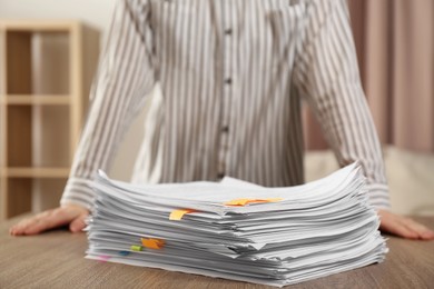 Photo of Woman and stack of documents on wooden table indoors, closeup