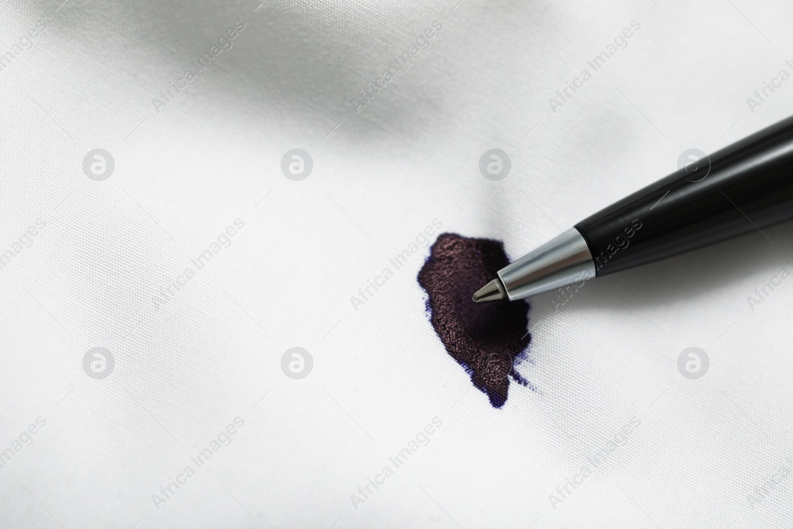 Photo of Pen and stain of black ink on white shirt, top view. Space for text