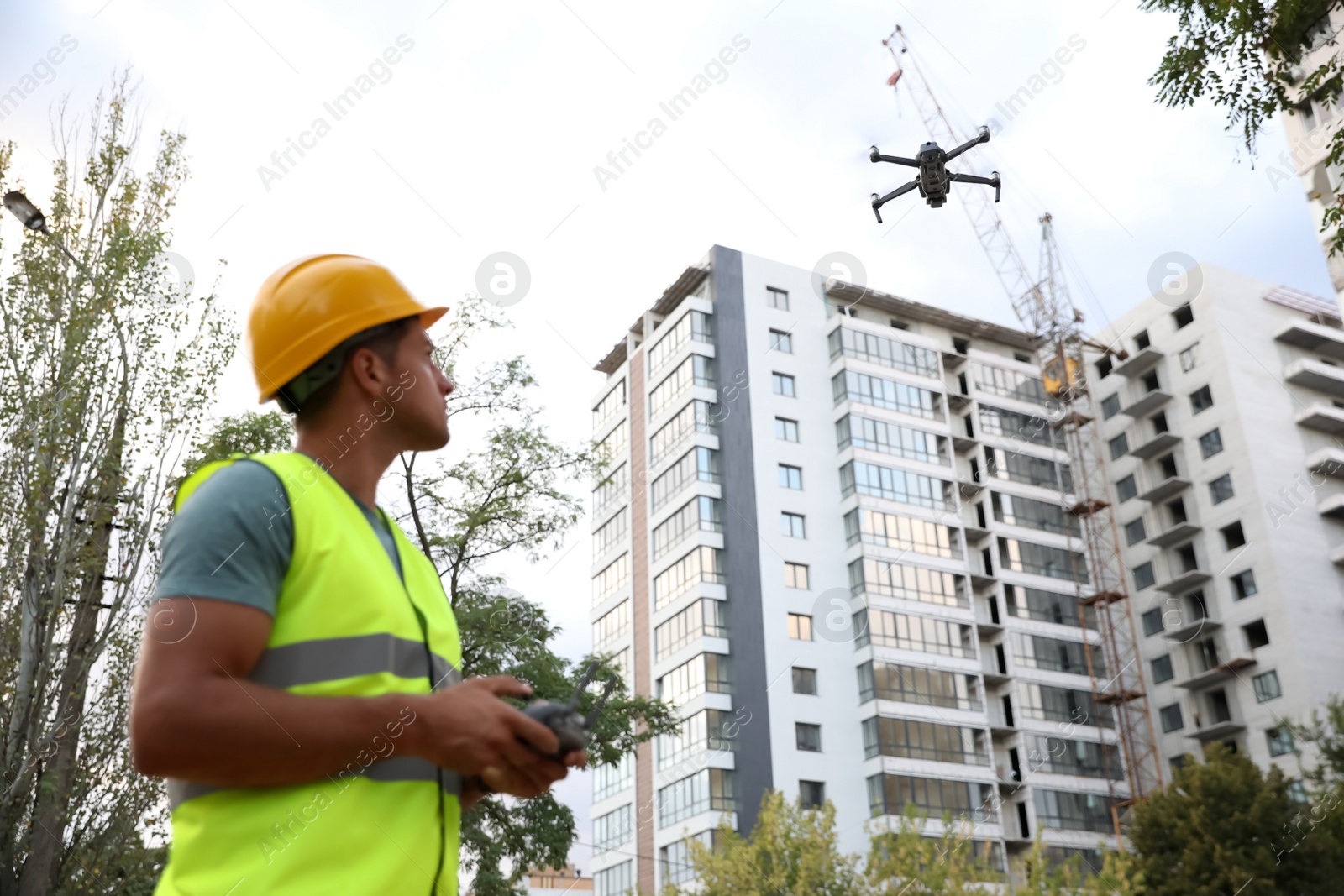 Photo of Builder operating drone with remote control at construction site. Aerial survey