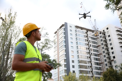 Builder operating drone with remote control at construction site. Aerial survey