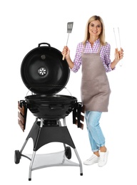 Woman in apron with barbecue grill and utensils on white background