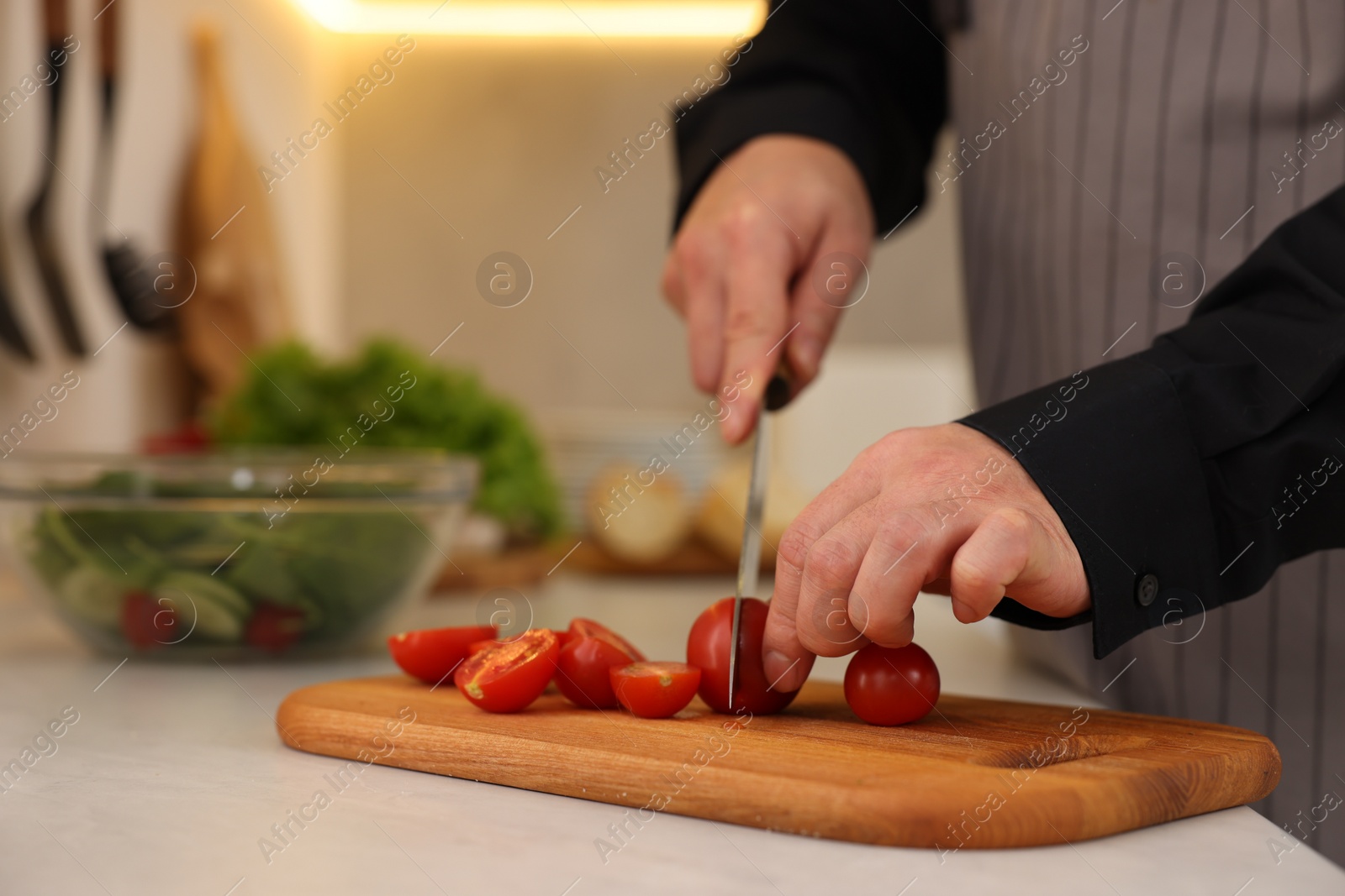 Photo of Cooking process. Man cutting fresh tomatoes in kitchen, closeup and space for text