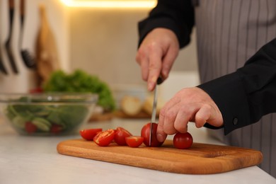 Photo of Cooking process. Man cutting fresh tomatoes in kitchen, closeup and space for text