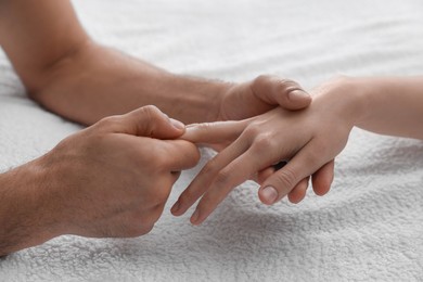 Photo of Woman receiving hand massage on soft towel, closeup