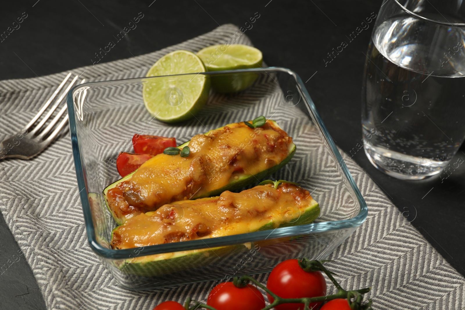 Photo of Baking dish with stuffed zucchinis served on black table