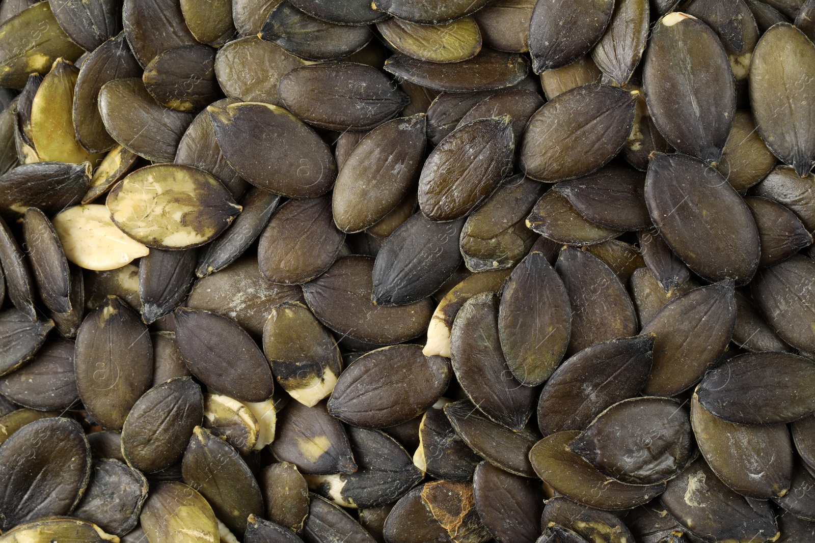 Photo of Many peeled pumpkin seeds as background, top view