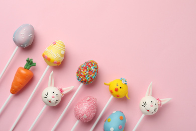 Photo of Delicious sweet cake pops and space for text on pink background, flat lay. Easter celebration