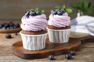 Photo of Sweet cupcakes with fresh blueberries on wooden table