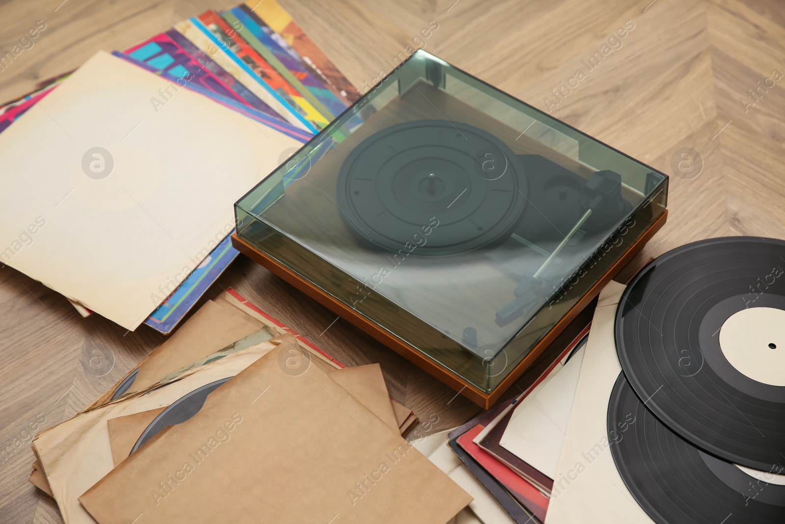 Photo of Stylish turntable with vinyl records on floor