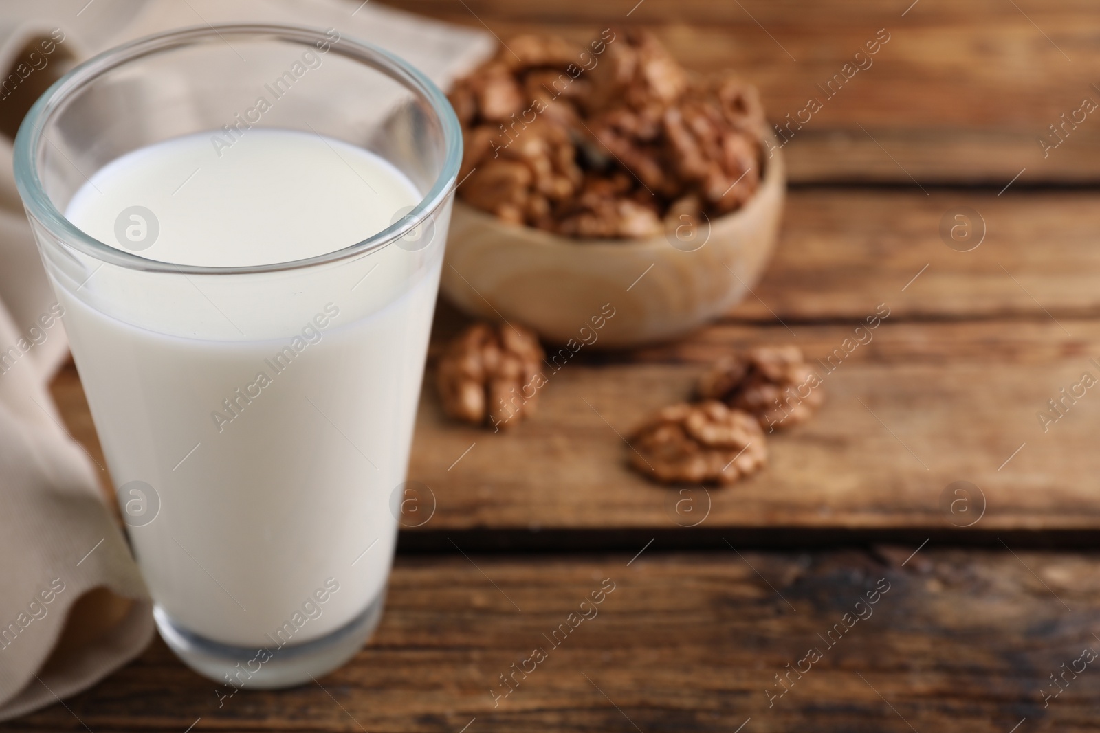 Photo of Glass of walnut milk on wooden table, closeup. Space for text