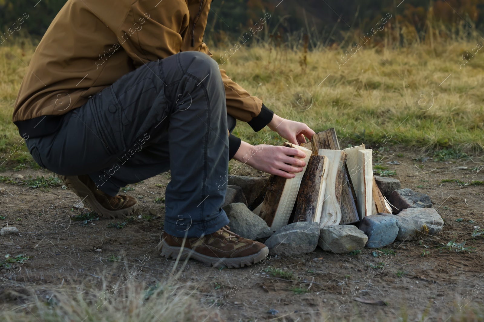 Photo of Traveler making bonfire with dry wood outdoors, closeup