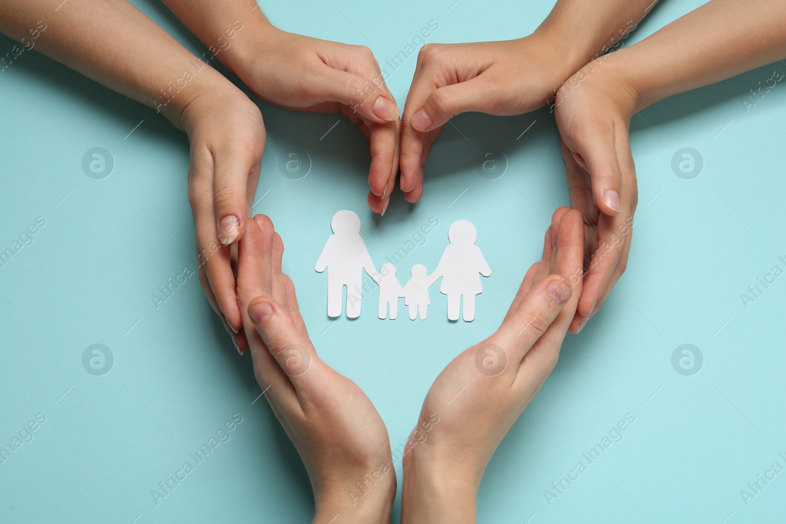 Photo of People with paper family cutout on light blue background, top view