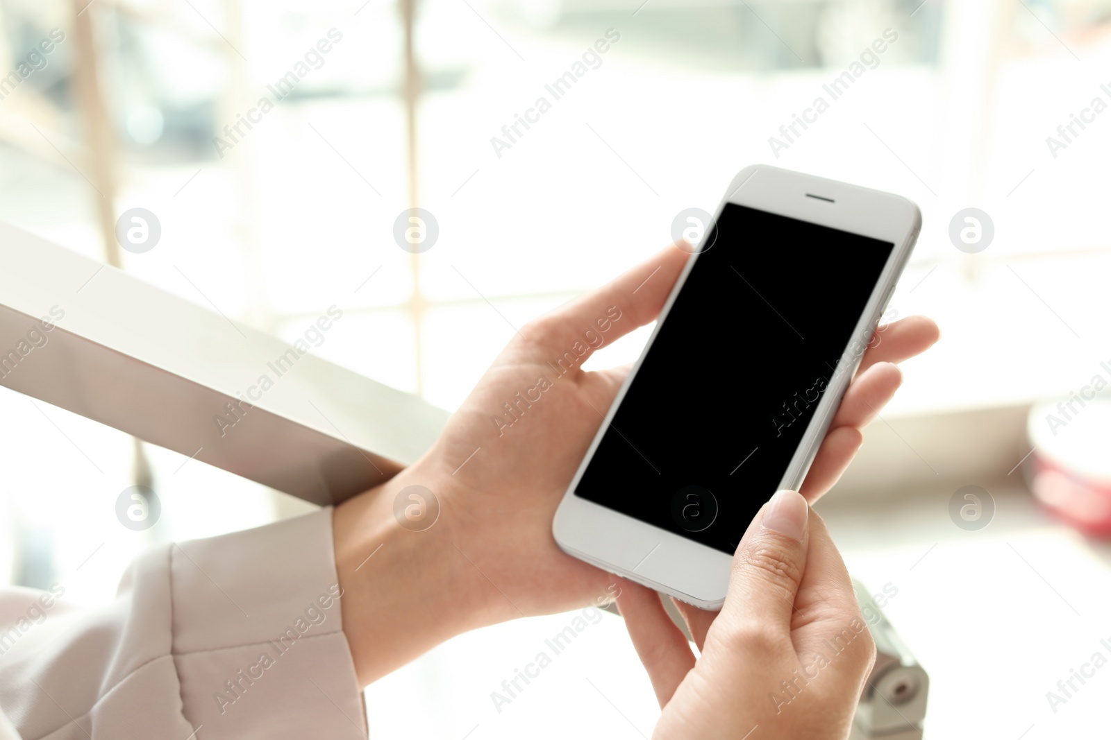 Photo of Woman holding smartphone with blank screen on blurred background. Mockup for design