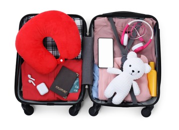 Photo of Soft travel pillow, hat, passports and other items in open suitcase isolated on white, top view