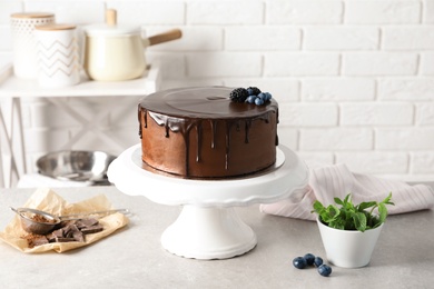 Fresh delicious homemade chocolate cake with berries on table against brick wall