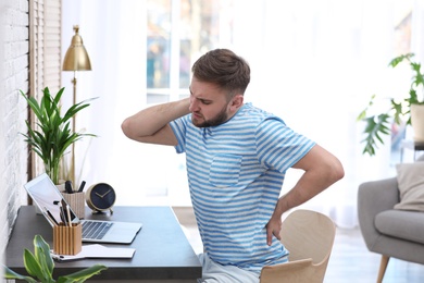 Photo of Young man suffering from back pain in office