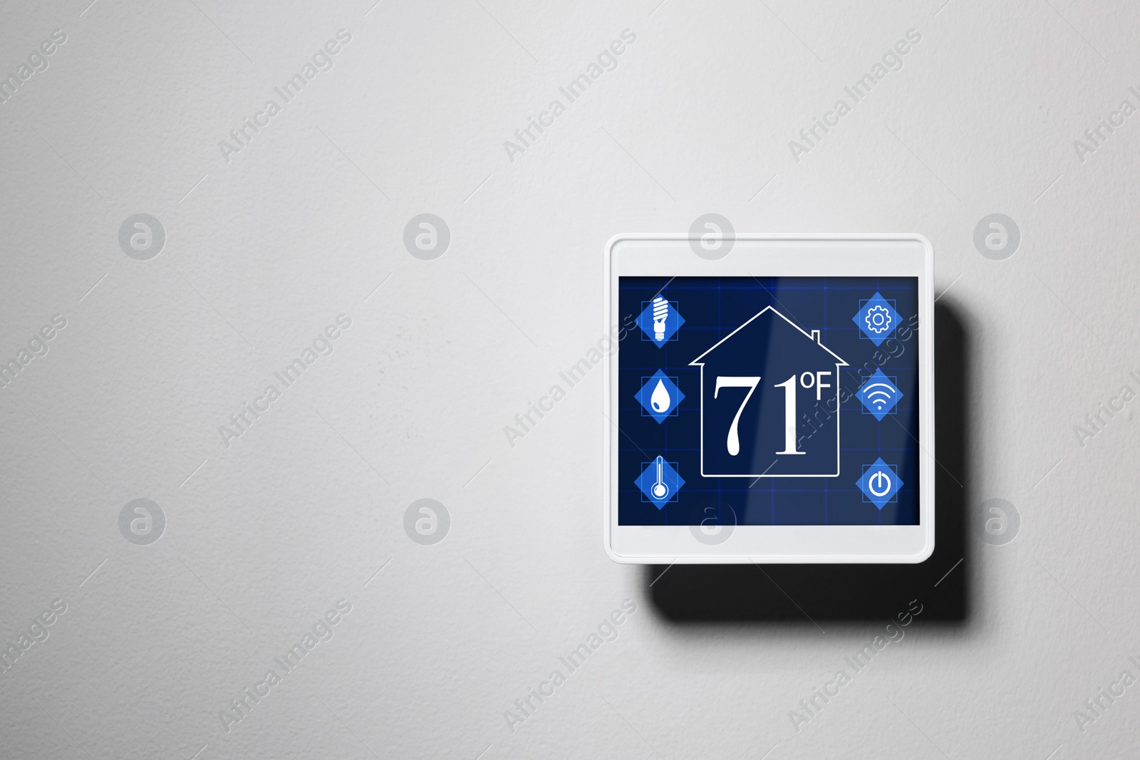 Image of Thermostat displaying temperature in Fahrenheit scale and different icons. Smart home device on white wall, space for text