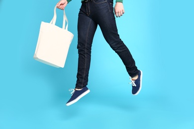 Photo of Young man with eco bag jumping on blue background, closeup