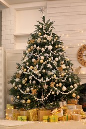 Decorated Christmas tree with gift boxes in room