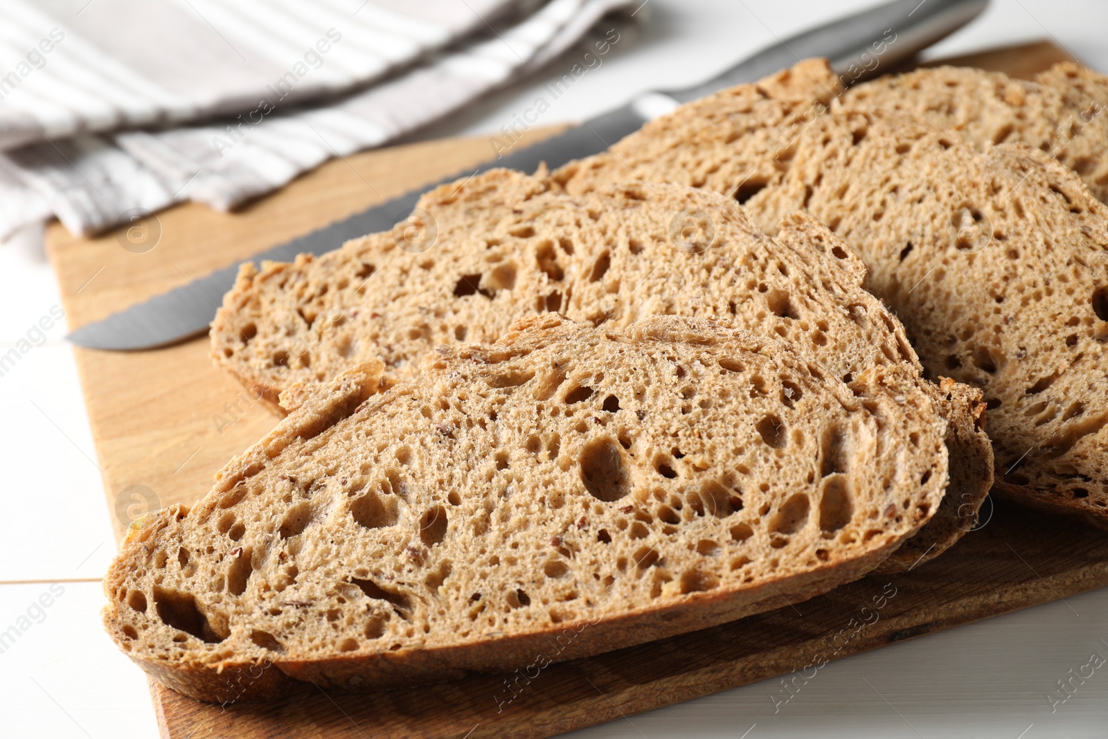 Photo of Freshly baked cut sourdough bread on white wooden table, closeup