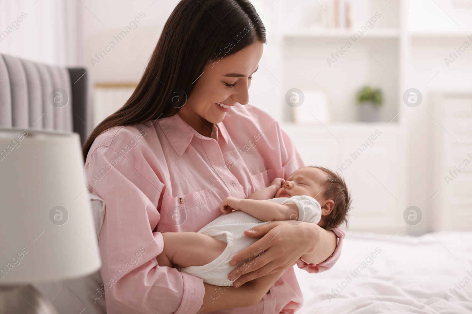 Photo of Mother with her sleeping newborn baby on bed at home