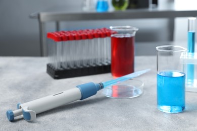 Photo of Laboratory analysis. Micropipette, petri dish, beakers and test tubes on light grey table