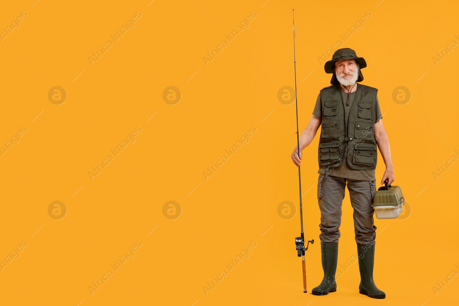 Photo of Fisherman with rod and box for fishing tackle on yellow background, space for text